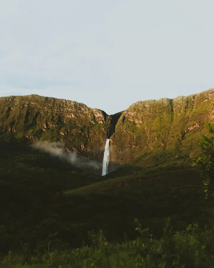 Cachoeira alta despencando de um paredão verde, paisagem de serra em Minas Gerais