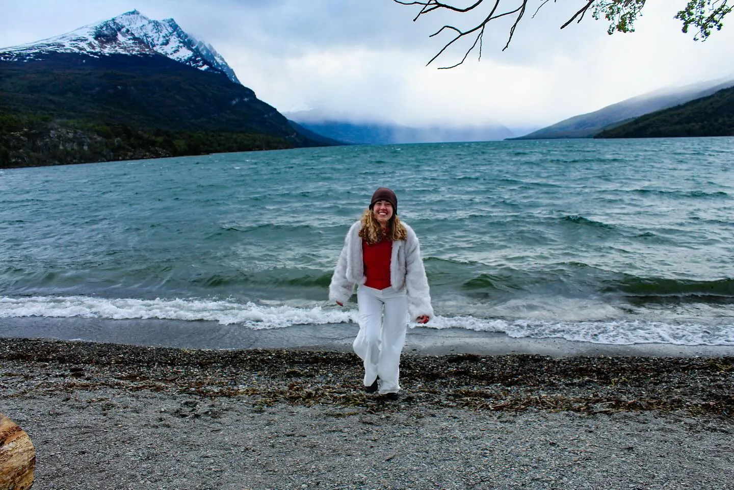 Sarah na praia de um lago com montanha nevada no Parque Nacional Tierra del Fuego
