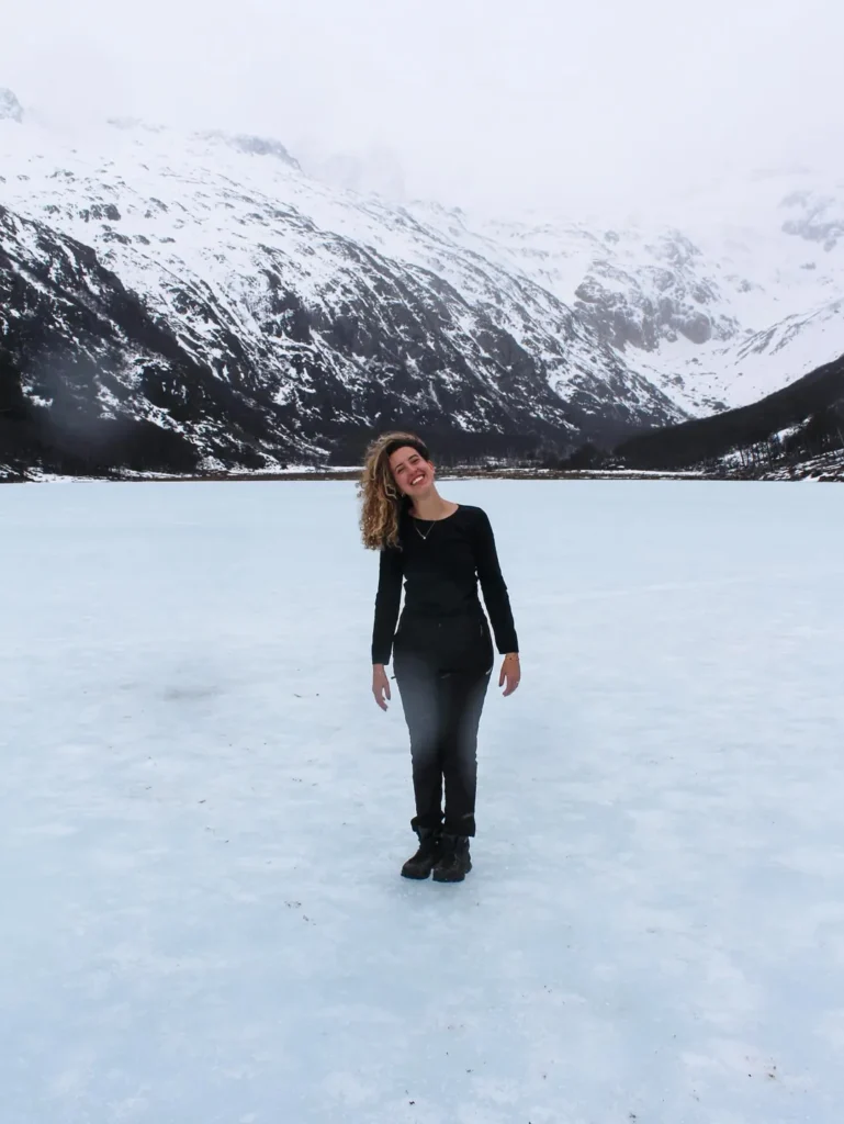 Sarah em pé sobre a Laguna Esmeralda congelada, cercada de montanhas nevadas