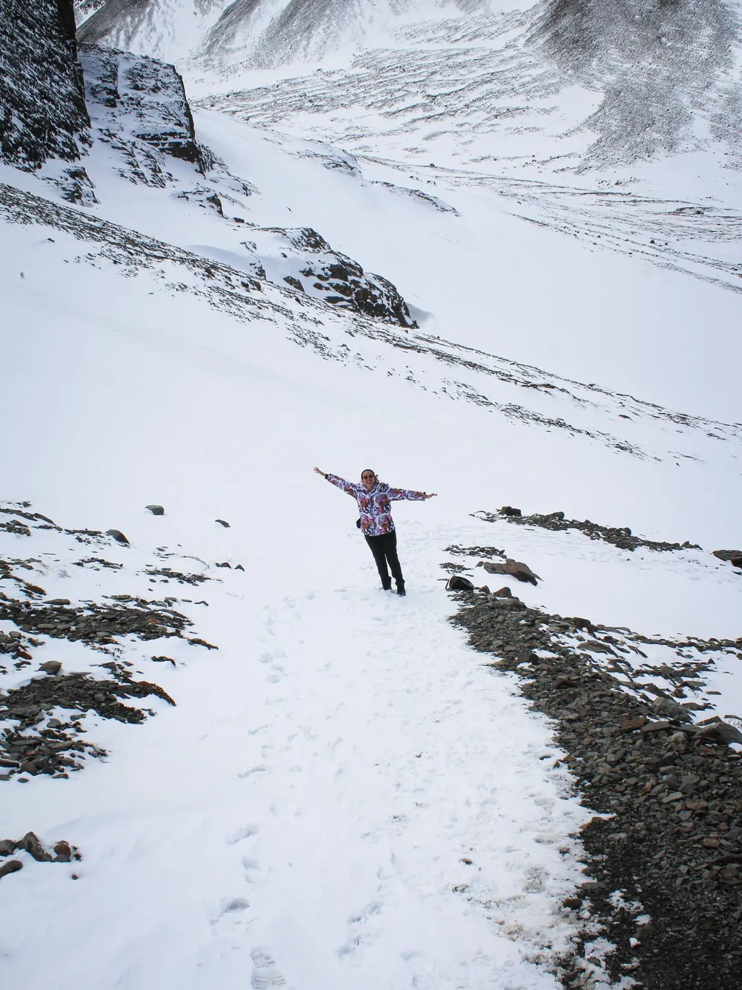 Sarah de braços abertos numa trilha coberta de neve perto de Ushuaia